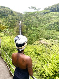 a woman looking out over a waterfall in hawaii