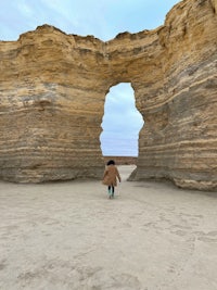 a person standing in front of a large rock formation